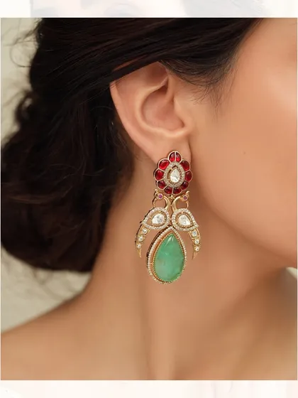 A pair of elegant earrings featuring a peacock-wing design with a pear-shaped emerald drop and red floral top.