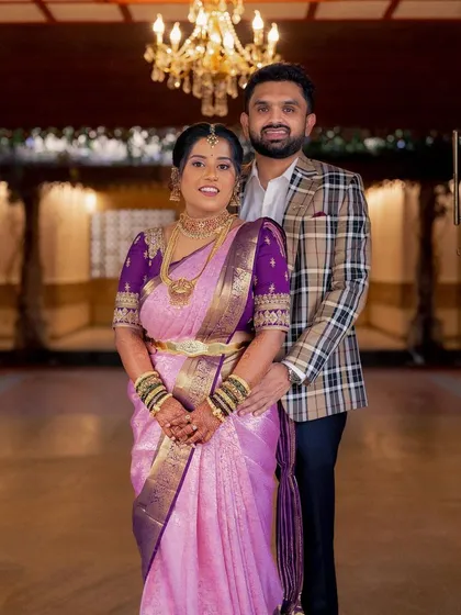 The perfect couple shot. Her traditional South Indian engagement look, with the rich purple blouse and glowing makeup, stands out beautifully against the classic architecture.