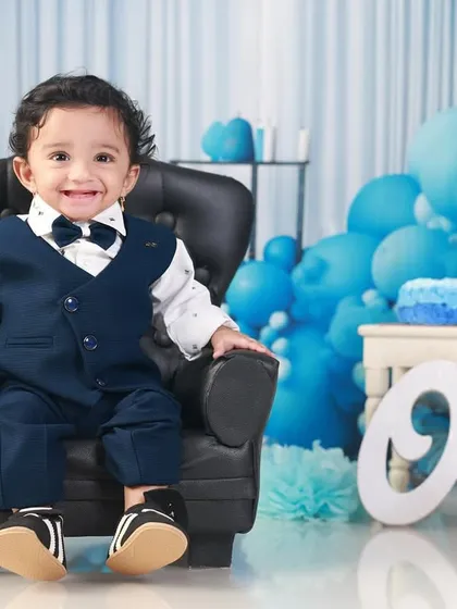 A happy, "clean" portrait before the cake smash, with the little boy smiling brightly in his smart suit and bow tie.