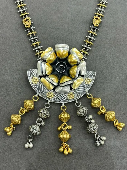An abstract take on my dual-tone style. This necklace features a semi-circular silver base with intricate carvings, topped with abstract gold and silver nuggets and finished with dangling dual-tone beads.