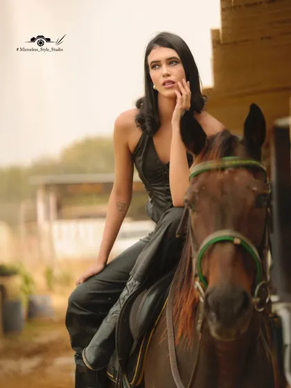 A thoughtful pose of a model on horseback, captured in the soft light of the stables.