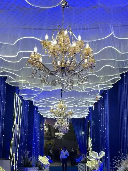 I believe the entrance sets the tone for the entire wedding. This is a grand walkway I designed, featuring royal blue drapes, elegant chandeliers, and a dreamy, wave-like ceiling with integrated lighting.