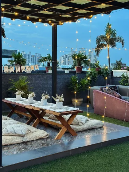 The rooftop transforms beautifully in the daylight. This boho-chic setup with low picnic tables and plush cushions is perfect for a sun-kissed brunch, high-tea, or a serene daytime gathering against the Gurugram skyline.