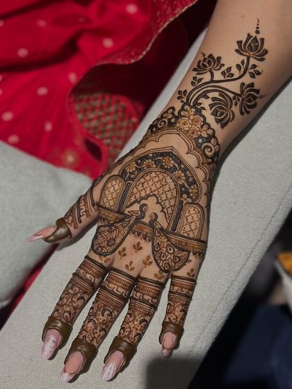 A stunning Karwachauth design featuring a peacock in a jharokha (window) with a floral vine extending up the arm. It's the perfect blend of elegance and tradition.