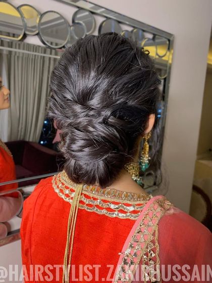 This messy, textured updo features a fishtail braid woven into a low bun. It's a modern and chic style, perfect for a bridesmaid or a wedding guest.