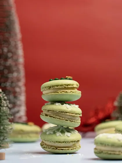 A stack of green macarons against a bold red background, creating a festive Christmas color palette. This type of minimalist, color-blocked shot is modern and striking.