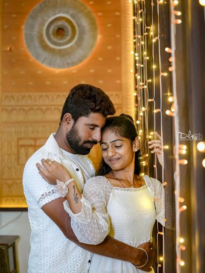 A sweet, intimate moment for a couple in all-white, with the warm glow of indoor lights creating a cozy feel.