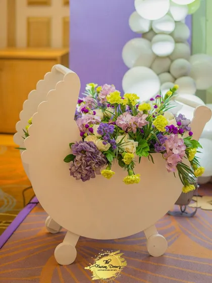 This large, white baby pram cutout is a fantastic photo prop and decor element. I filled it with a beautiful arrangement of fresh flowers in shades of purple, yellow, and white to match the event's pastel color scheme.
