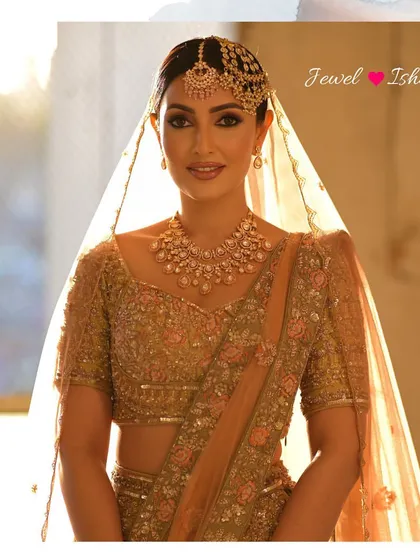 A sun-kissed portrait of a bride in a golden-hour glow. She wears a beautiful uncut Polki necklace with a matching passa and maang tikka.