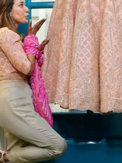 A fun and quirky shot of a bridesmaid admiring the bride's lehenga. It’s a candid moment of excitement and friendship that adds a touch of humor to the wedding album.