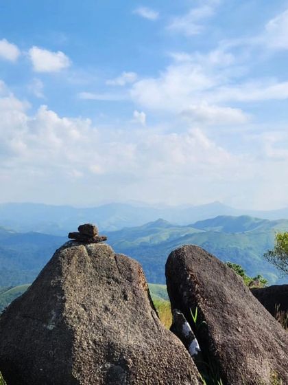 Balanced stones on a rock, with the layers of mountains in the background.