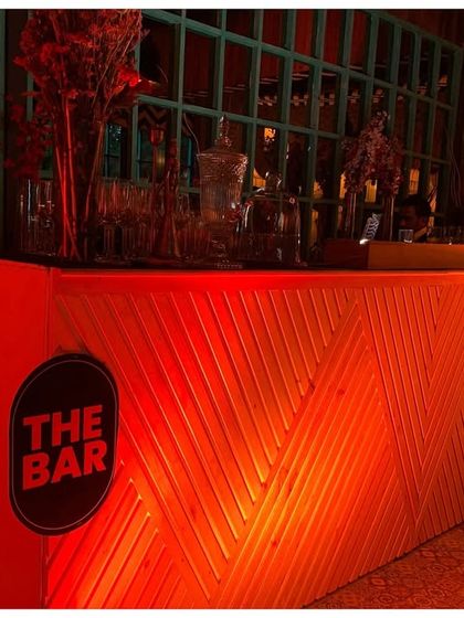 For this 40th birthday, I designed a custom bar with geometric wood paneling, lit from within by intense red light. The bold 'THE BAR' sign made it an unmissable feature of the party.
