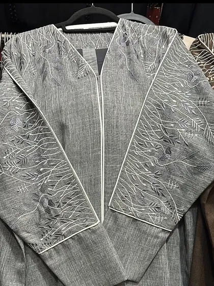 This grey zip up abaya features intricate white embroidery in a beautiful branch and leaf pattern across the sleeves and front panels.