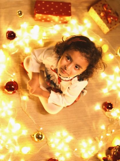 Lost in the magic of twinkling lights. This creative shot captures a child's wonder during the holiday season, surrounded by a circle of warm fairy lights.