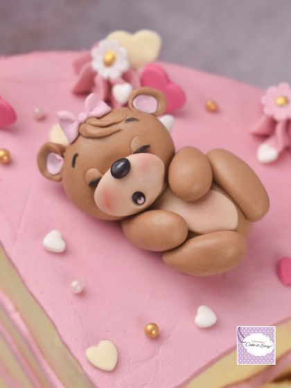 A close-up of the sleeping teddy bear topper for a 3-month birthday cake. The cake itself is covered in buttercream, with just the decorations made from fondant.