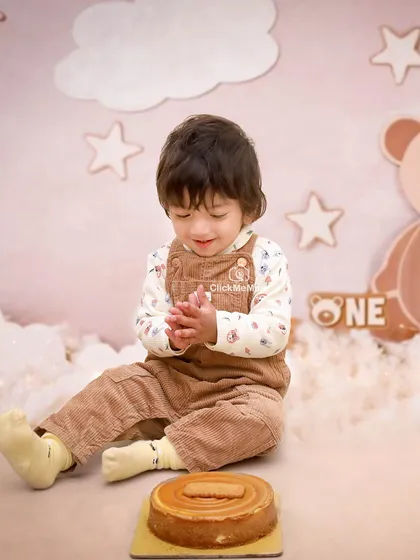 A moment of quiet clapping amidst the birthday excitement. This sweet bear-themed setup with soft clouds and stars creates a dreamy backdrop for a first birthday.