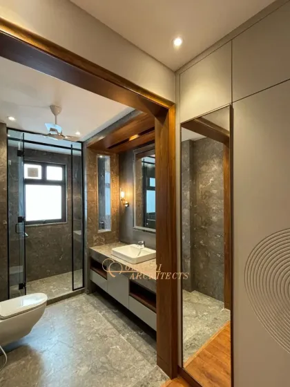 A modern bathroom design featuring dark grey marble, a wood-paneled ceiling accent, and a glass-enclosed shower.