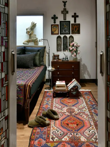 The bedroom in its winter theme, with darker, charcoal-grey furnishings and an antique Bhutanese textile on the bed. The decor changes with the seasons, reflecting a dynamic and lived-in approach to design.