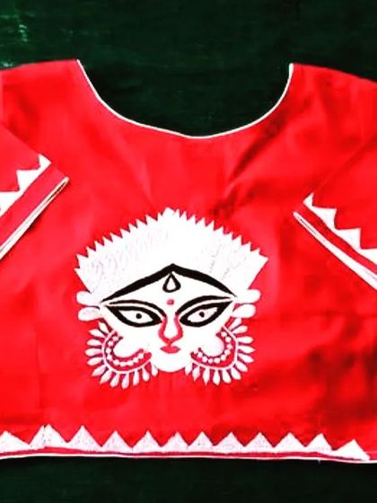 A simple yet powerful red blouse with a white applique design of Maa Durga's face. The zig-zag border on the sleeves and hem adds a modern design element.