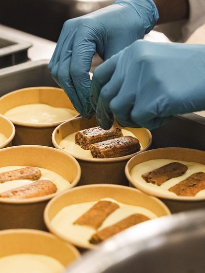 Placing coffee-soaked ladyfingers into the cups for our Tiramisu.
