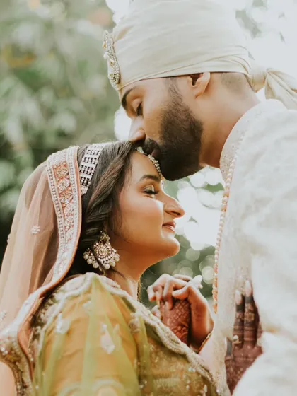 A tender forehead kiss. This classic, romantic pose is always beautiful, capturing a moment of quiet affection and protection between the couple.