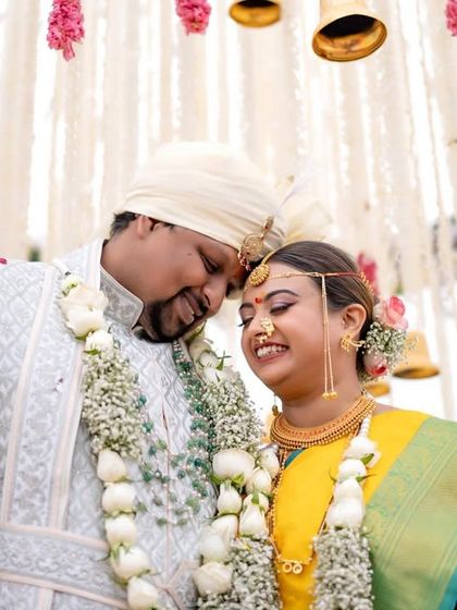 A beautiful portrait of the couple under a mandap decorated with bells and flowers, set against the open sky of Mussoorie.