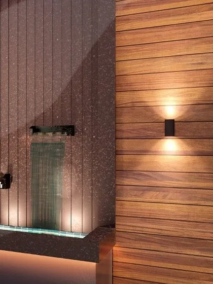 A close-up on material and lighting details. The warm uplight on the wooden paneling contrasts beautifully with the cool, smooth surface of the waterfall, showcasing our thoughtful use of light.