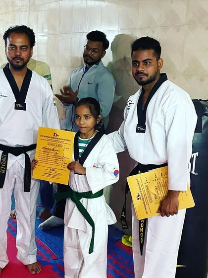 A student receiving her green belt certificate from me and Master Yogesh. We work as a team to guide our students towards their goals.
