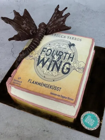 A different perspective of the 'Fourth Wing' book cake, showing the full sculpture of the chocolate dragon and the detailed, edible pages of the book.