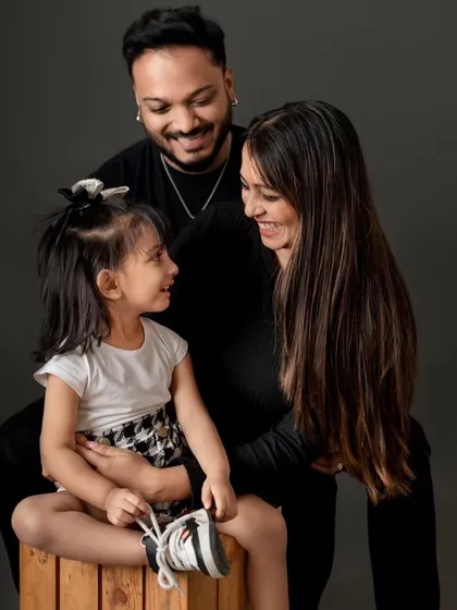 A beautiful, intimate family portrait against a classic dark backdrop. This style creates a timeless and dramatic look that focuses entirely on the family's expressions.