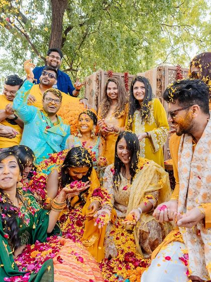 The happy chaos of a Haldi, with the couple and their friends covered in turmeric and petals.
