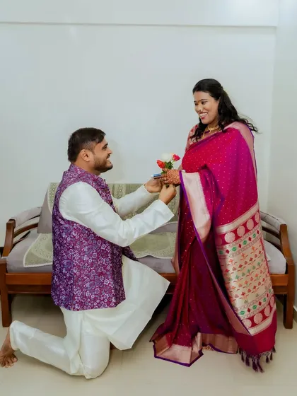 A sweet proposal moment during an intimate home engagement. The groom offers flowers to his bride-to-be.