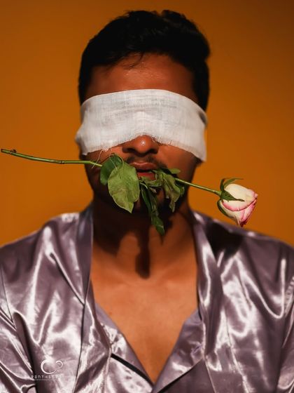 The contrast between the soft rose and the blindfold is the central theme of this artistic and thought-provoking portrait.