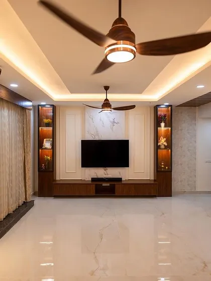 This living room is a testament to our belief in creating cohesive, beautiful spaces. From the custom TV unit with illuminated display shelves to the elegant wall paneling and ambient lighting, every detail works together to create a warm and inviting atmosphere.