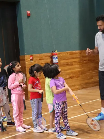 A group of young girls listens attentively as their coach explains a new drill, showcasing our structured group coaching for kids.