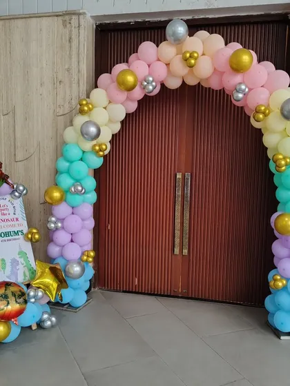 A colorful balloon arch at the entrance of the dinosaur-themed party, welcoming guests to the celebration.