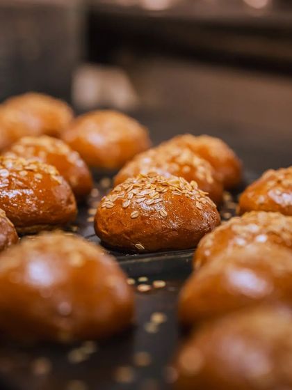 A tray of our freshly baked burger buns, their soft, wheatish-brown shimmer setting them apart.