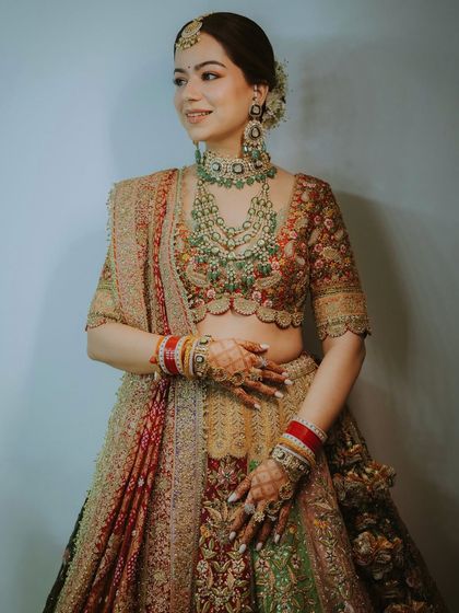 A detailed portrait of a bride showcasing her elaborate multi-layered necklace and heavily embroidered lehenga.