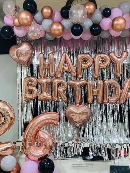 A closer view of the rose gold "Happy Birthday" foil balloons and the layered balloon garland.