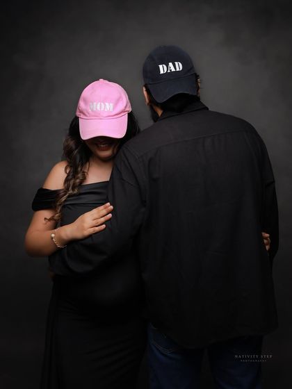 A fun and anonymous-style couple's portrait with "Mom" and "Dad" hats. This is a playful way to celebrate your new titles.