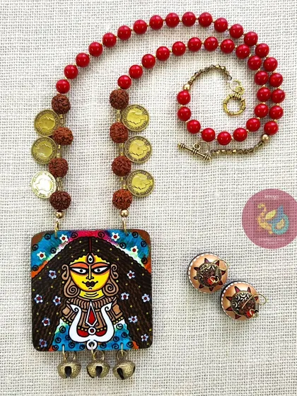 Feel the power of the goddess with this Durga necklace set. I painted this piece to be bold and protective, using a strong red and yellow palette. The set includes a detailed MDF pendant with brass ghungroos, wooden jhumkas, and sacred rudraksha beads.
