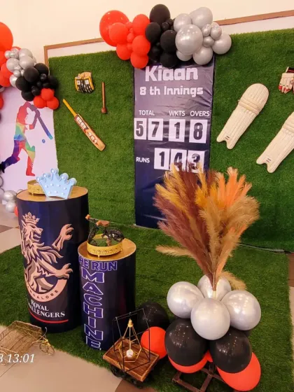The full setup for the cricket-themed party, including RCB-themed plinths and a personalized scoreboard.