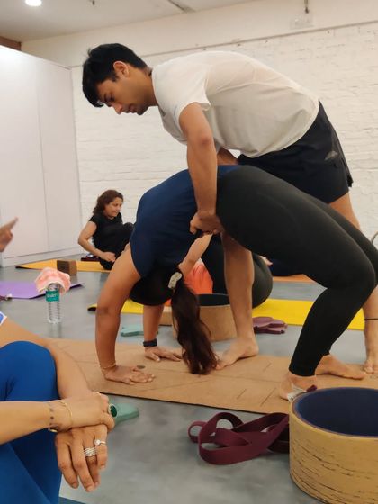 Personal assists are a key part of my workshops. Here, an instructor helps a student safely deepen her Urdhva Dhanurasana (Wheel Pose), providing support and encouragement.