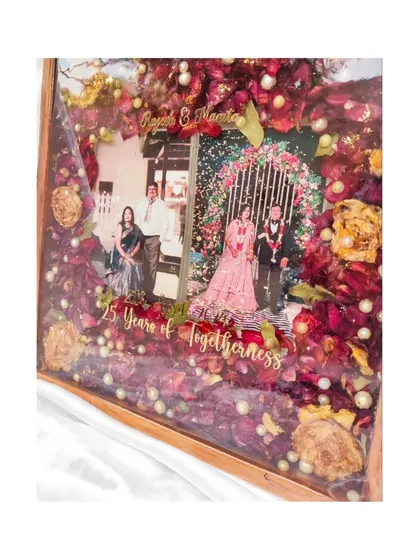 A 25th anniversary is a milestone of love worth celebrating and preserving. For this special gift, I used the couple's original wedding flowers, photos, and names in a beautiful teakwood resin frame to honor their incredible journey together.