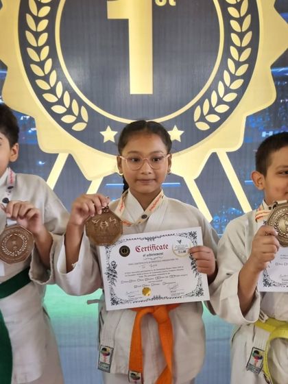 Three young champions proudly displaying their medals and certificates. It's wonderful to see them support each other's success.
