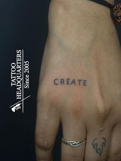 The word "CREATE" in a simple, clean font on the hand, a powerful one-word reminder for any artist or creator.