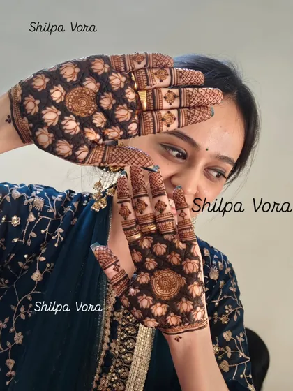 The joy on a client's face is the best reward. Here, she is showcasing a beautiful full-palm design filled with lotus flowers, a symbol of purity and beauty.
