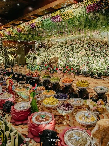 An expansive view of a hall filled with flowers, with a ceiling of hanging florals and a massive, dense floral backdrop.