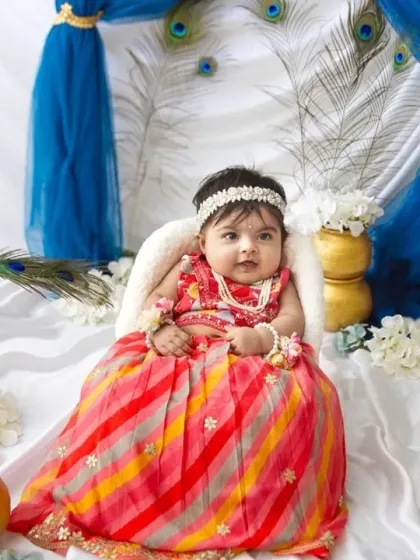 A happy little smile from our Janmashtami princess. The vibrant blues and whites of the backdrop make the entire scene feel so divine.