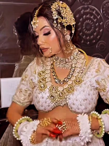 A bride in a white lehenga adorned with a gold and kundan jewellery set, including a unique passa-style headpiece. This look is perfect for a Nikkah ceremony or reception.